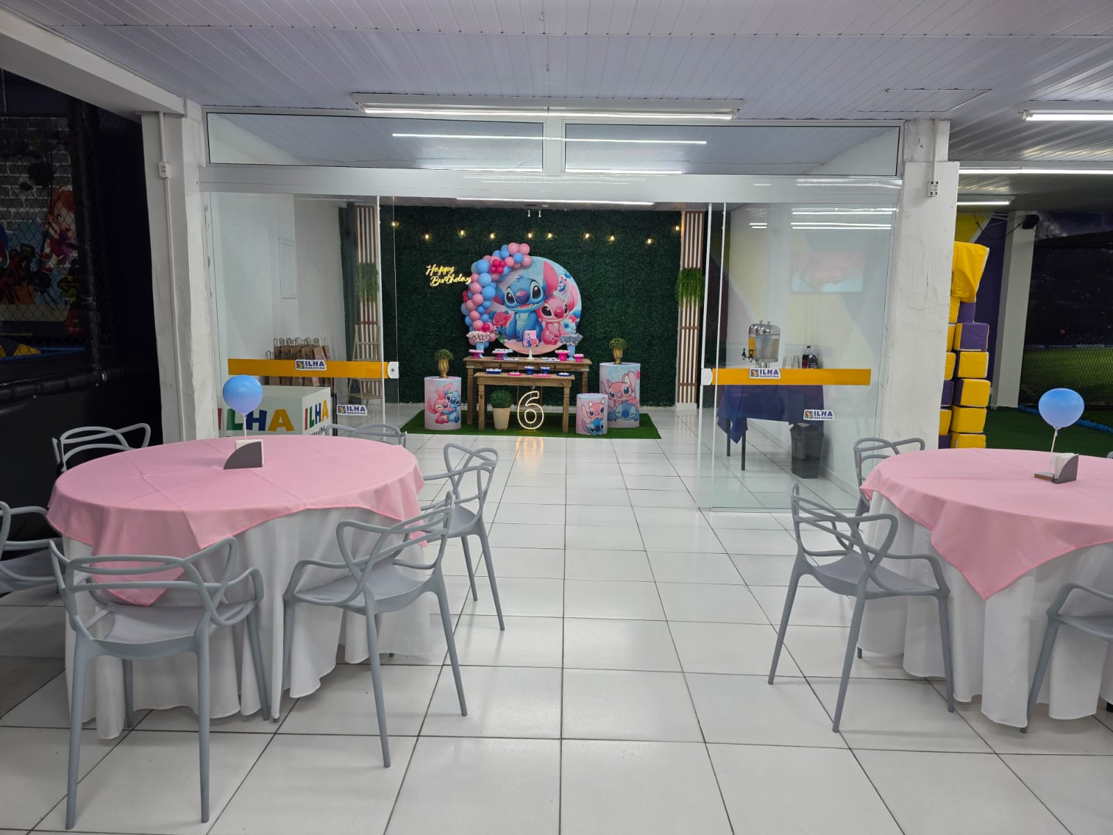 Salão de festas com mesas e espaço para decoração